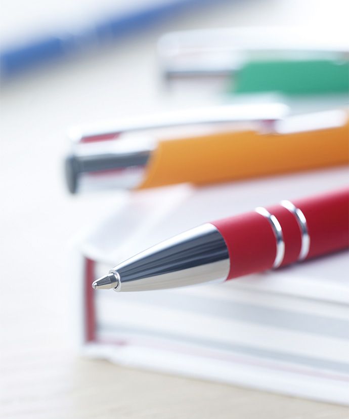 Bolígrafos de metal de distintos colores sobre un libro